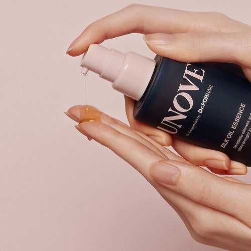 UNOVE Silk Oil Essence being dispensed onto hand, showcasing its lightweight texture for effective hair repair and shine.